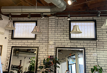 Salon being renovated, with workers installing screen sheer shades on a large shop window.